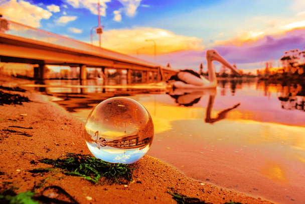 Um belo tiro de foco seletivo de uma bola de cristal refletindo o pôr do sol de tirar o fôlego com cores únicas
 - Foto, Imagem