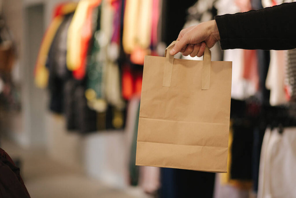 Χέρι με τσάντα χειροτεχνίας σε κατάστημα ρούχων. Ανδρική τσάντα hilding με την αγορά - Φωτογραφία, εικόνα