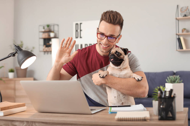 Beau homme avec chien chiot mignon et ordinateur portable à la maison
 - Photo, image