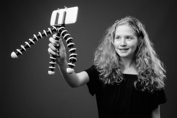 Studioaufnahme einer jungen schönen blonden Teenagerin vor grauem Hintergrund in schwarz-weiß - Foto, Bild