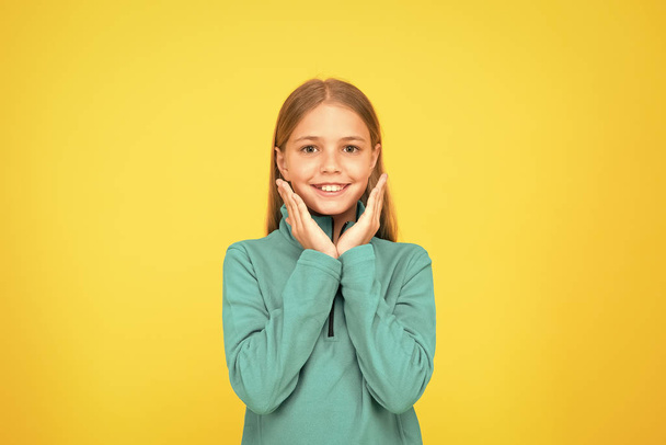 Adorable girl beautiful face. Childrens shop store mall. Goods for teens. Upbringing and education. Little girl. Small child on yellow background. Child care concept. Preteen girl smiling expression - Фото, изображение