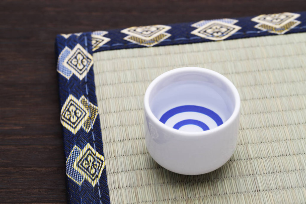 Saké japonais en céramique traditionnelle tasse d'ochoko sur table tatami
  - Photo, image