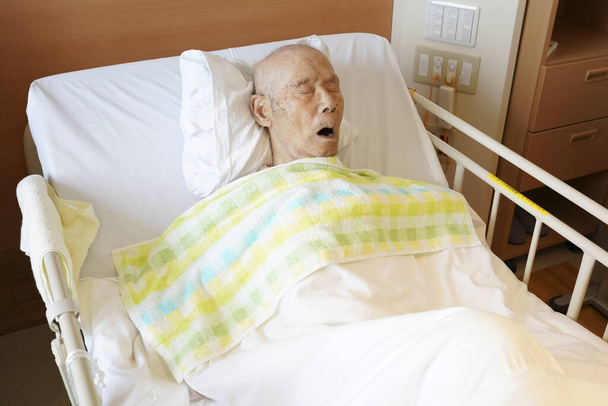Yatakta yatıp hastanede uyuyan yaşlı Japon hasta. - Fotoğraf, Görsel