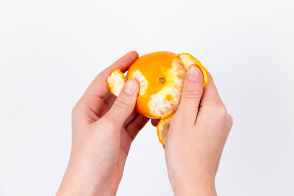 Женская рука чистит апельсин. Рука, чтобы очистить мандарин. Есть
 - Фото, изображение
