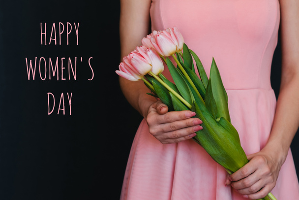 bukiet kwiatów różowych tulipanów w rękach dziewczyny. Pozdrowienia z tekstem Szczęśliwego Dnia Kobiet - Zdjęcie, obraz