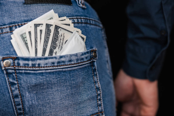 condom and banknotes money dollars in back pocket men jeans - Fotó, kép