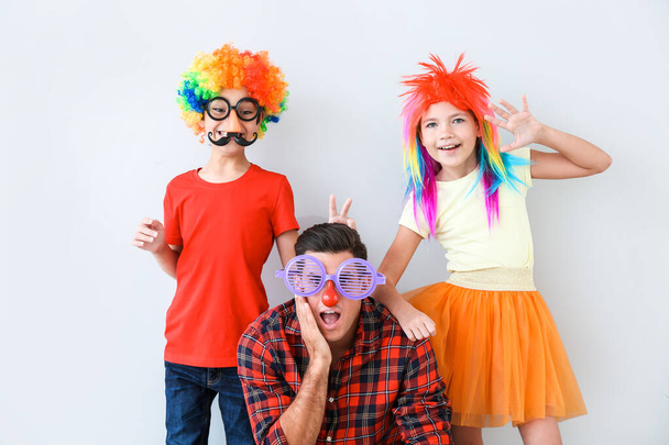 Family in funny disguise on light background. April fools' day celebration - Photo, Image