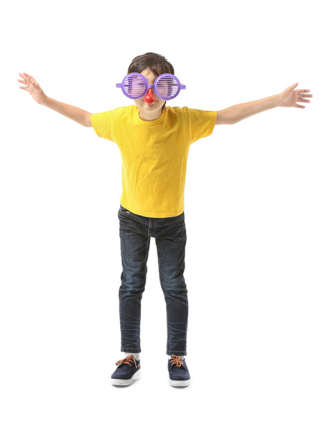Little boy in funny disguise on white background. April fools' day celebration - Foto, Imagen