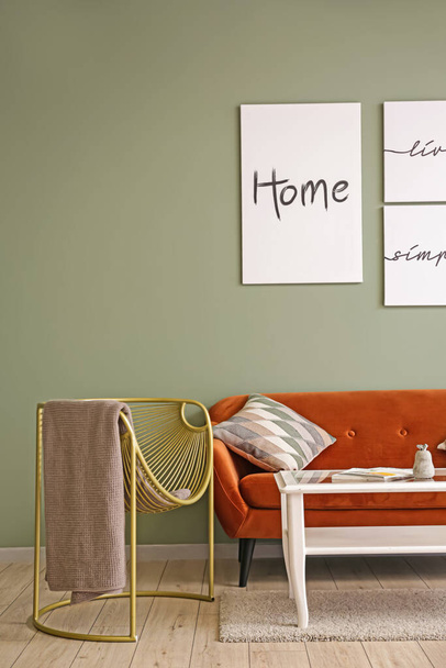 Інтер'єр сучасної кімнати зі стильним кріслом, диваном і столом біля кольорової стіни
 - Фото, зображення