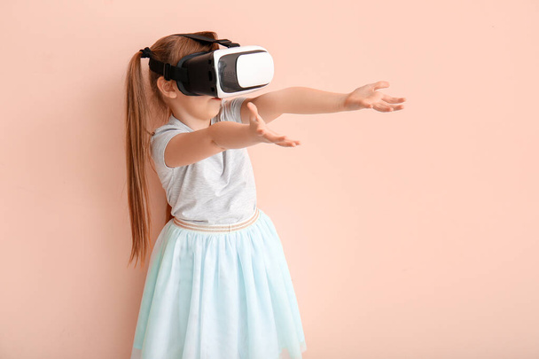 kleines Mädchen mit Virtual-Reality-Brille auf farbigem Hintergrund - Foto, Bild