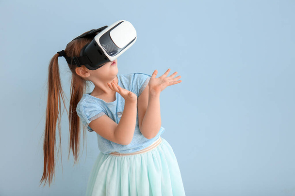 Klein meisje met virtual reality bril op kleur achtergrond - Foto, afbeelding