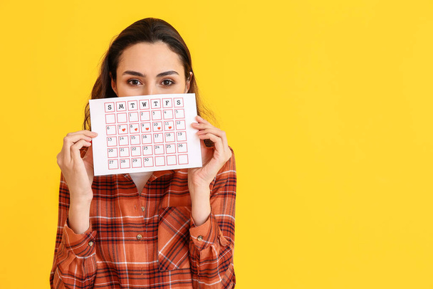 Młoda kobieta z kalendarzem menstruacyjnym na tle koloru - Zdjęcie, obraz