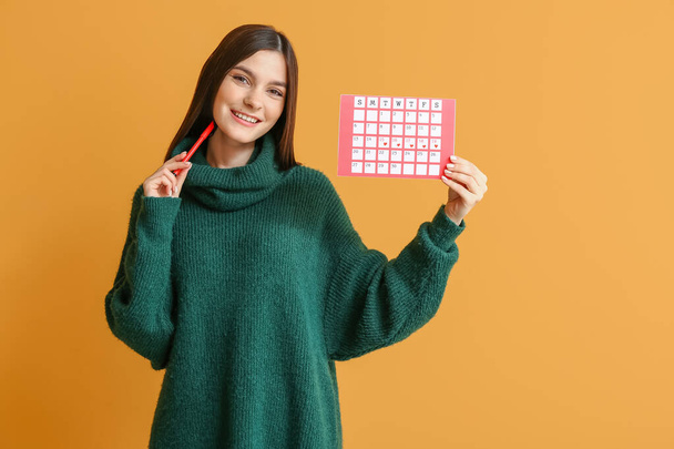 Jeune femme avec calendrier menstruel sur fond de couleur
 - Photo, image