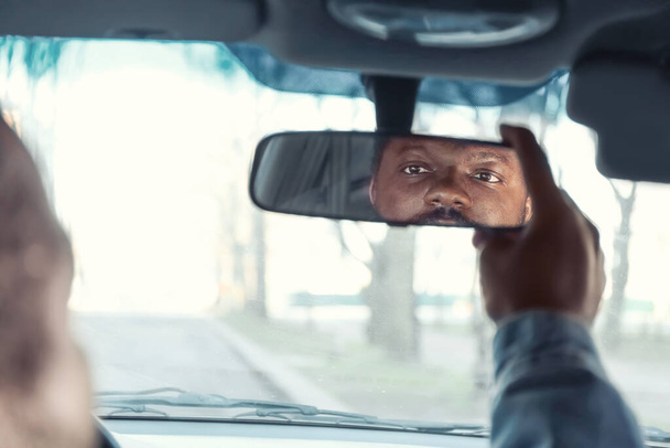 Conductor ajustando el espejo retrovisor en el coche
 - Foto, imagen