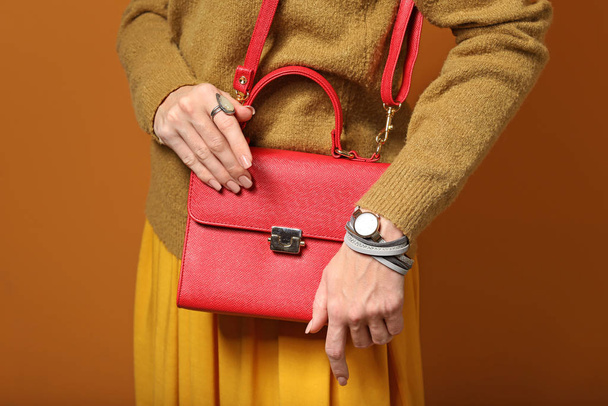 Young woman in warm sweater and with stylish bag on color background - Foto, Imagen