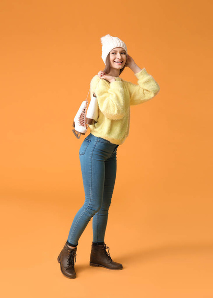 Beautiful young woman with ice skates on color background - Valokuva, kuva