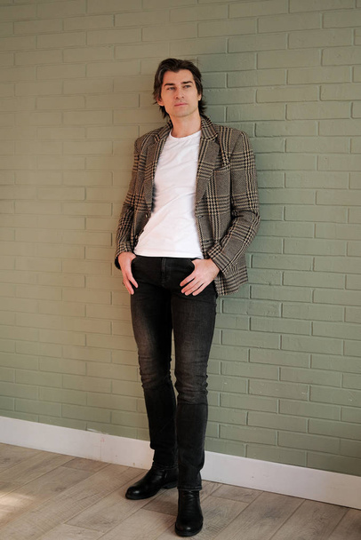 Tall handsome man standing next to grey wall - Foto, Imagen