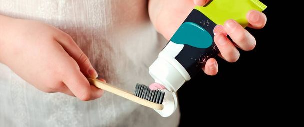 as mãos da menina com pasta de dentes e escova de dentes eco. escova de dentes de bambu para projeto de resíduos zero
. - Foto, Imagem