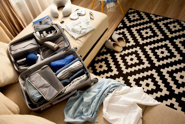Open grey suitcase with different clothes packed for journey at  - Φωτογραφία, εικόνα