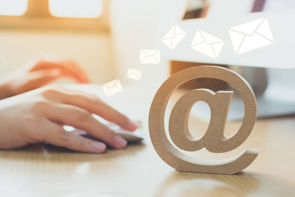 Concept de marketing par e-mail, main en utilisant un message d'envoi d'ordinateur avec symbole d'adresse e-mail en bois et icône enveloppe
 - Photo, image
