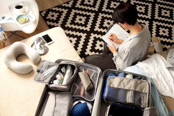 Open grijze koffer met verschillende kleding verpakt voor onderweg bij  - Foto, afbeelding