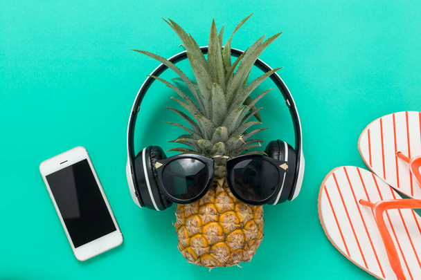 Vacaciones de verano de fondo Concepto, Teléfono con piña, gafas y chanclas En un fondo verde y amarillo vista superior
 - Foto, Imagen
