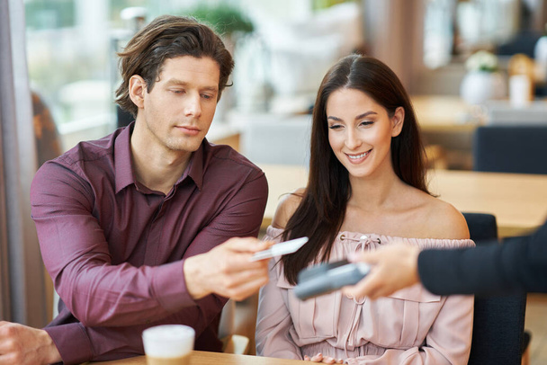 Pareja joven pagando con tarjeta de crédito en Café
 - Foto, Imagen