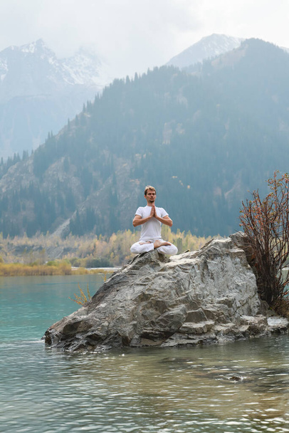 Homem zen jovem em meditação. Yoga ao ar livre no lago da montanha. Exercício Agni Stambhasana. - Foto, Imagem