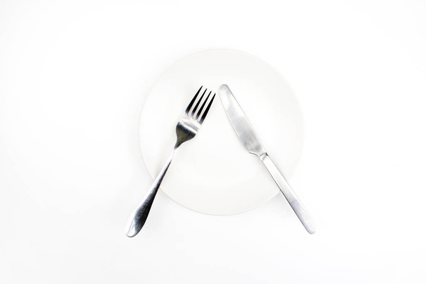 Forchetta e coltello su un piatto vuoto su fondo bianco
 - Foto, immagini