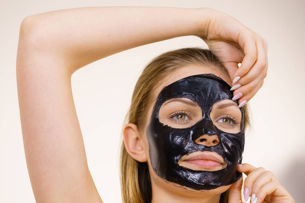 Girl removes black mask from face - Foto, imagen