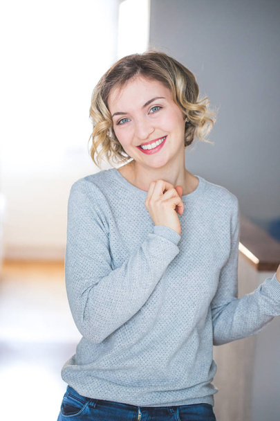 Cute young woman with blonde curly hair is happy about her new home  - Foto, afbeelding