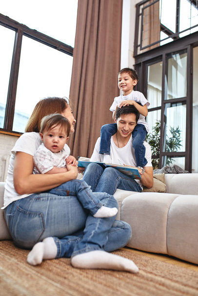 міжнародна сім'я вдома на дивані, обіймається і насолоджується життям. Щасливе сімейне життя
 - Фото, зображення