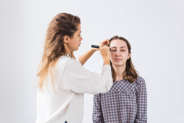 Beauty and cosmetics concept - Makeup artist doing professional make up of young woman - Φωτογραφία, εικόνα