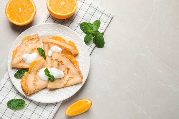 Delicious thin pancakes with oranges and cream on marble table, flat lay. Space for text - Φωτογραφία, εικόνα