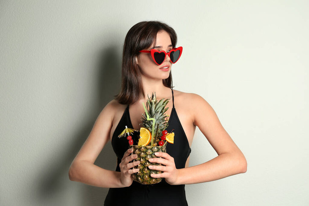 Beautiful woman in stylish swimsuit holding tropical cocktail on - Zdjęcie, obraz