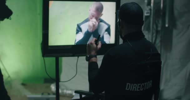 Regisseur gibt Anweisungen und beobachtet die Szene auf Monitor - Filmmaterial, Video