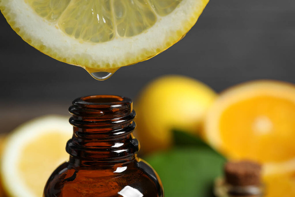 Citrus essential oil dripping from lemon slice into bottle, closeup - Φωτογραφία, εικόνα