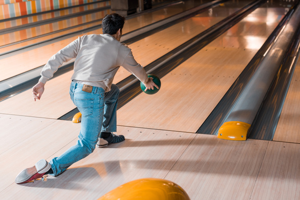 back view of young man throwing bowling ball on skittle alley - Φωτογραφία, εικόνα