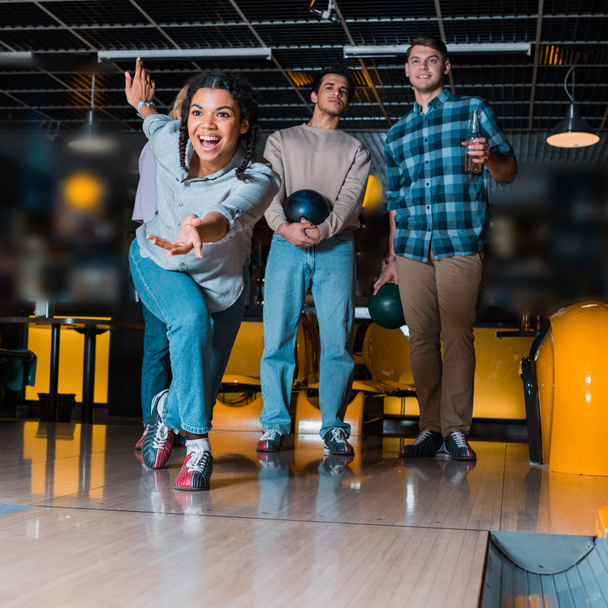 eccitata ragazza afroamericana lanciando bowling ciotola su skittle vicolo vicino amici multiculturali
 - Foto, immagini