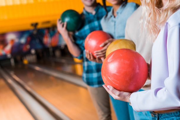 Bowling kulübünde dikilirken ellerinde bowling topları tutan çok kültürlü arkadaşların kesikli görüntüsü. - Fotoğraf, Görsel