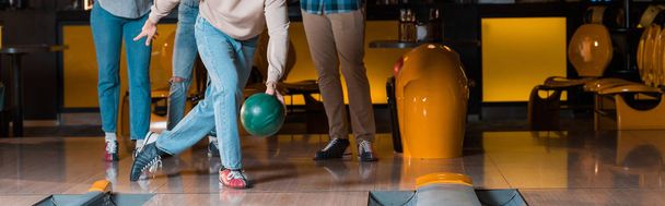 cropped view of man throwing bowling ball on skittle alley near multicultural friends, panoramic shot - Фото, зображення