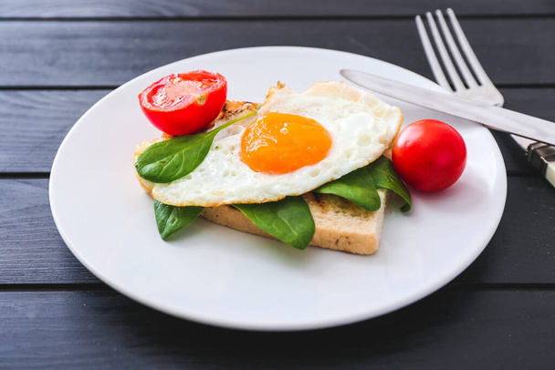 Смачне смажене яйце з підсмаженим хлібом та помідорами на тарілці
 - Фото, зображення