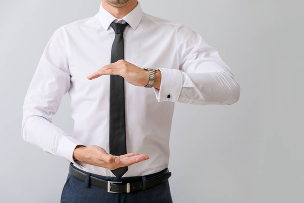 Young businessman holding something on grey background - Photo, Image