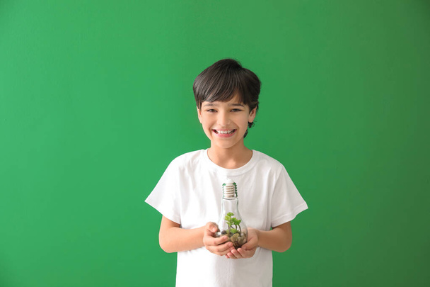 Μικρό αγόρι κρατώντας λάμπα με φυτό στο φόντο χρώμα. Γιορτή της Γης - Φωτογραφία, εικόνα