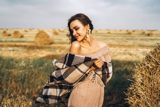 Portrait of a beautiful brunette in a dress and with a warm plai - Fotografie, Obrázek