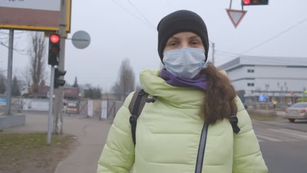 Protezione contro il coronavirus cinese in una città europea. Una giovane donna in un luogo pubblico si trova in una maschera medica in Germania. L'insorgenza dei sintomi del coronavirus. - Filmati, video
