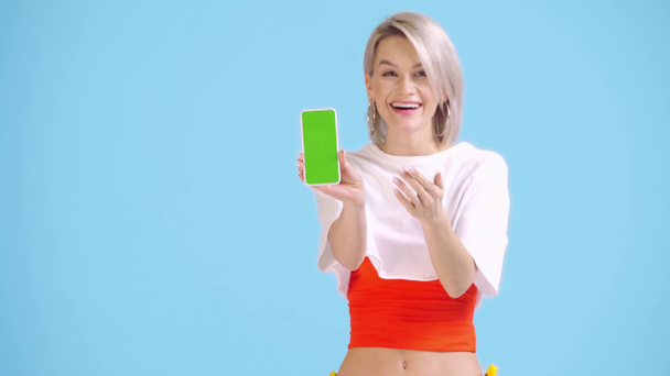 excitée fille pointant avec le doigt sur smartphone isolé sur bleu
 - Séquence, vidéo