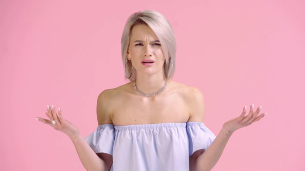 boos meisje tonen schouders gebaar en kijken naar camera geïsoleerd op roze - Video