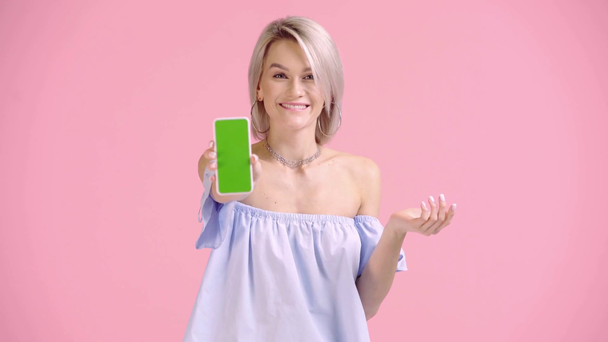 щаслива дівчина вказує пальцем на смартфон і показує добре ізольовані на рожевому
 - Кадри, відео
