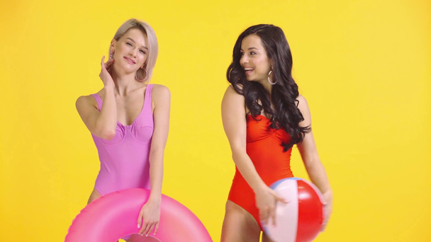 smiling girls in swimsuits posing and going away isolated on yellow - Footage, Video